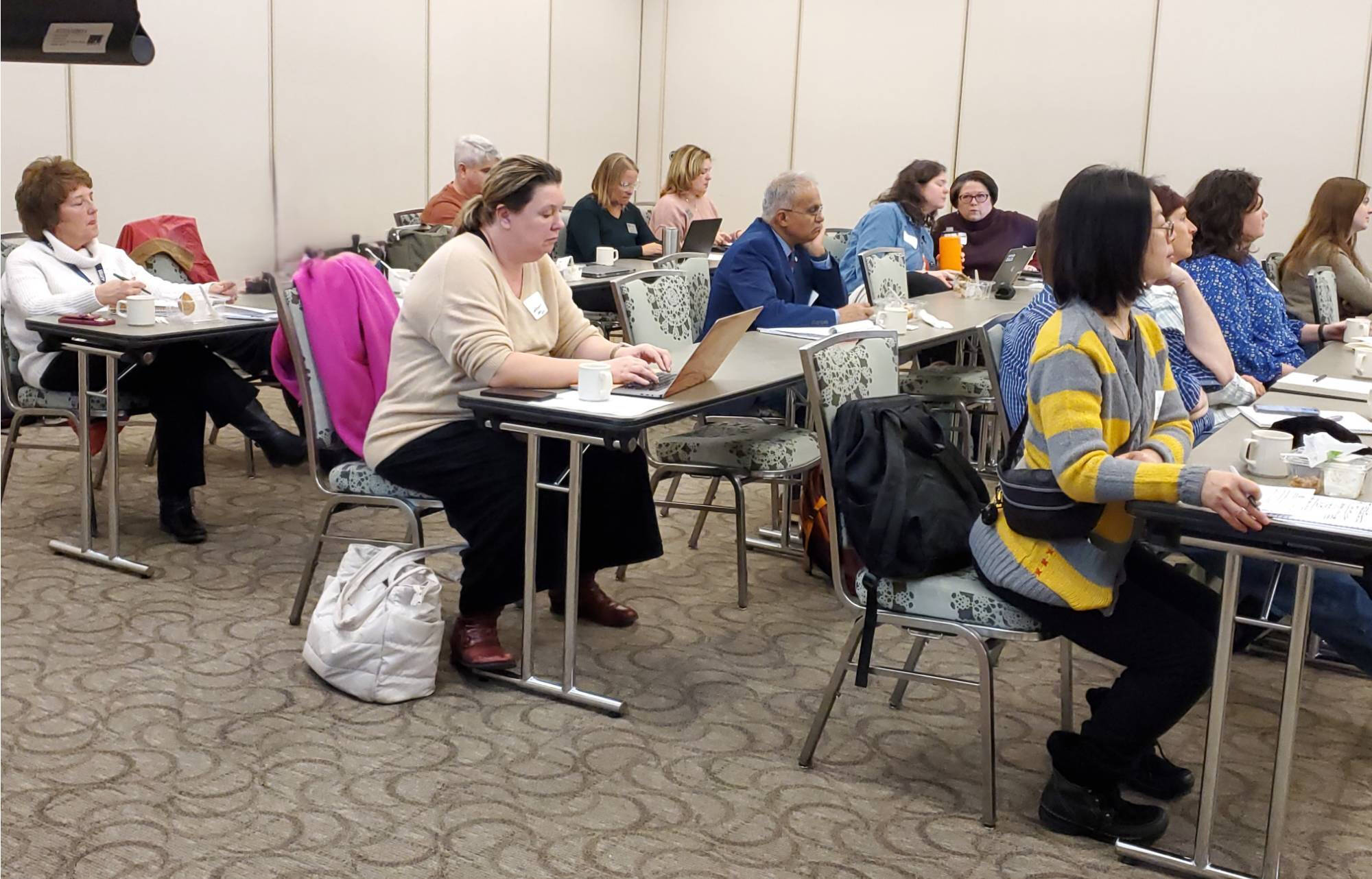 Conference attendees listening to and taking notes on a presentation
